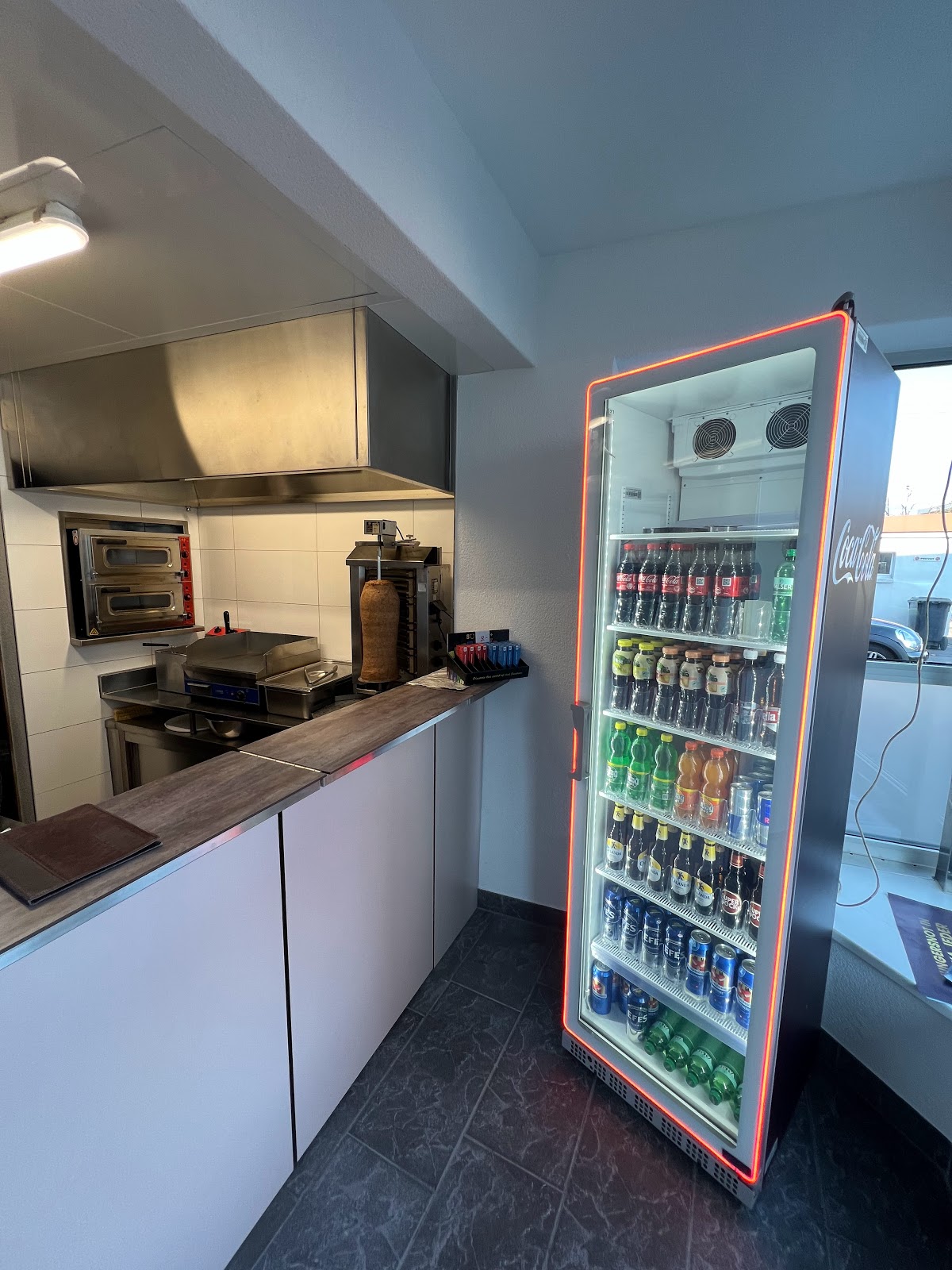 Offene Küche bei Musti's — Drehspiess und Kühlvitrine