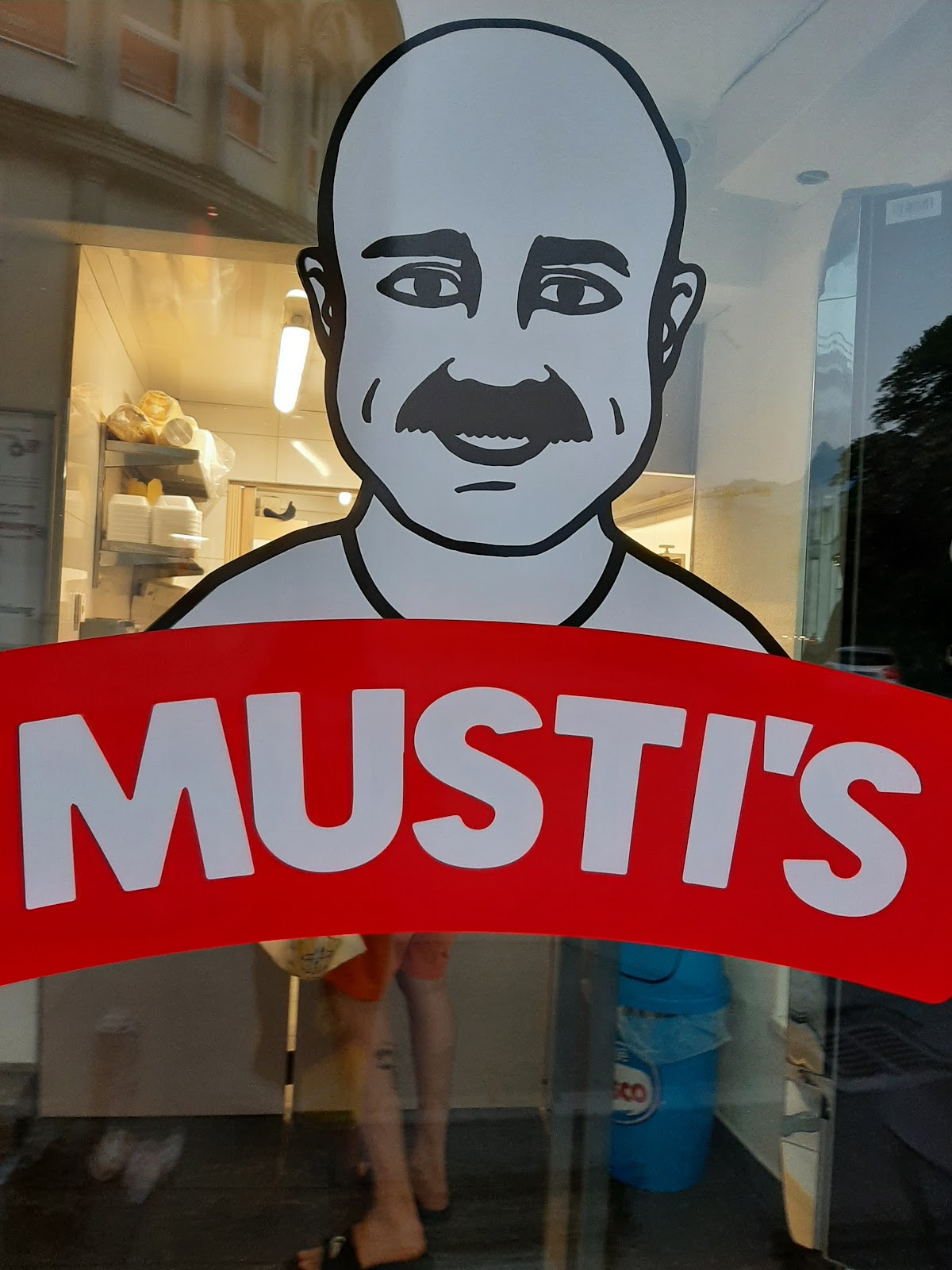 Musti's Schaufenster — Logo mit dem Gesicht des Inhabers